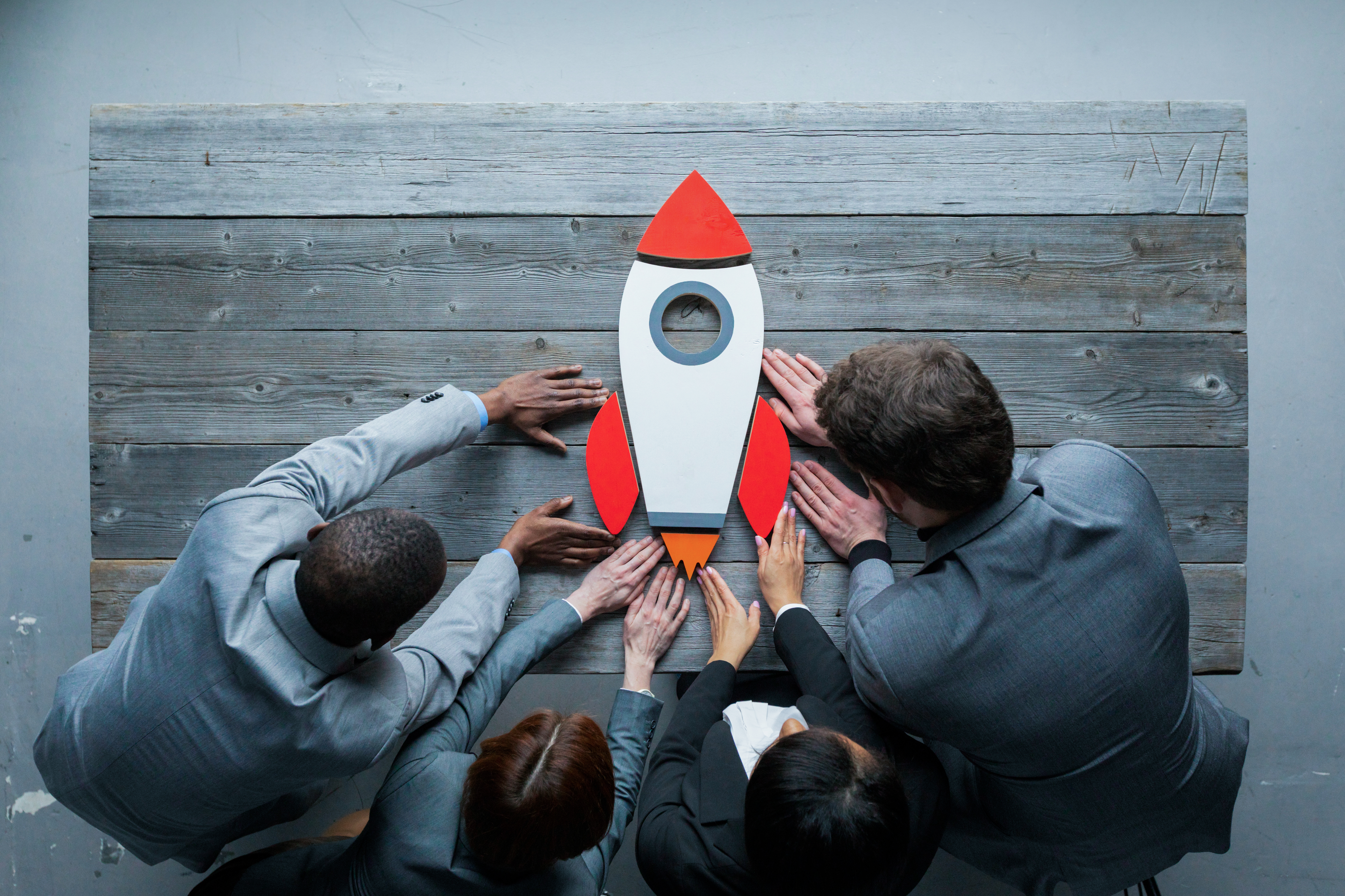 Foto einer einer Rakete auf Holztisch gestützt von Business Team  | Projektmarketing