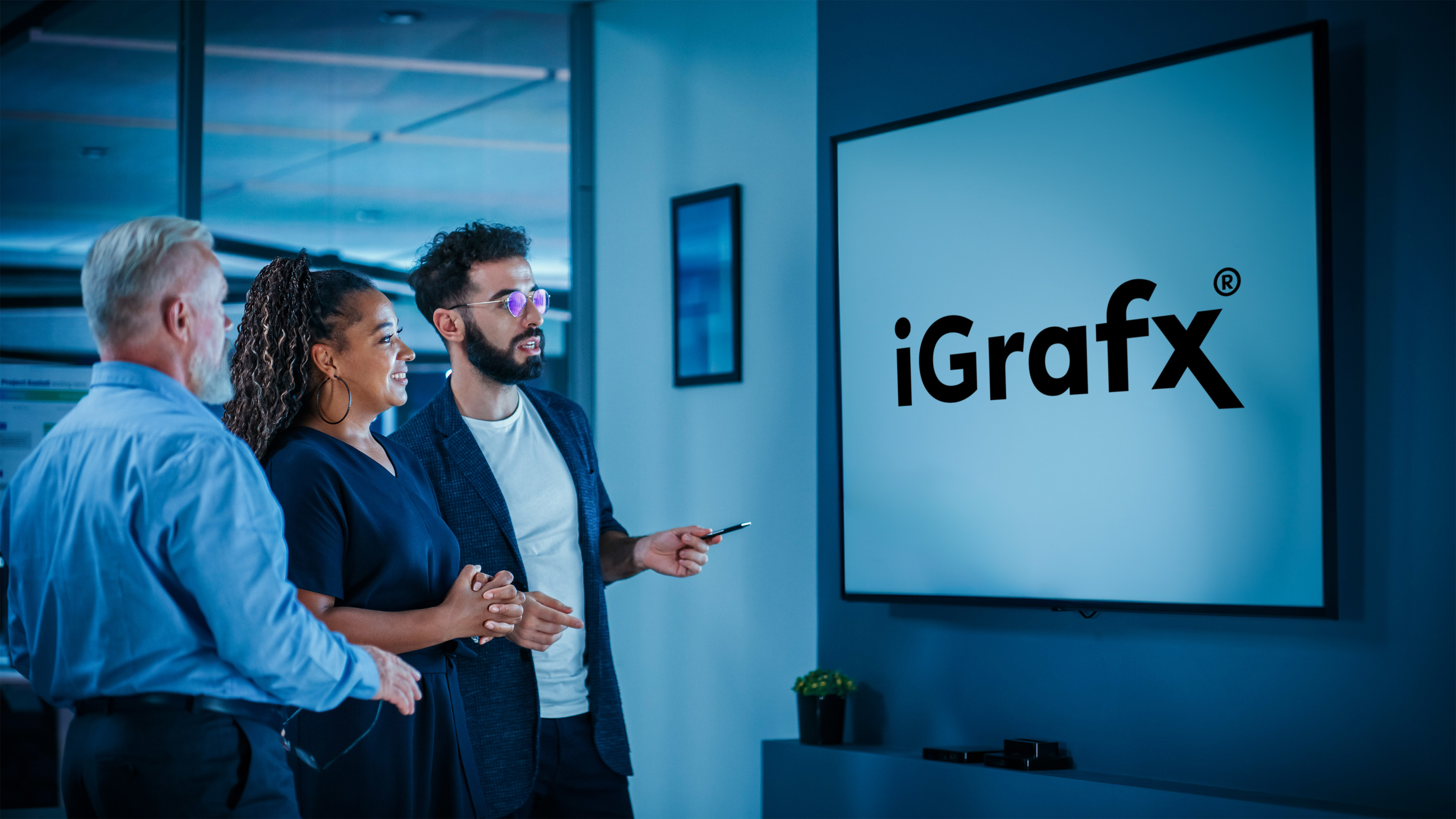 Foto eines Team Meetings vor Bildschirm, auf dem das iGrafx-Logo angezeigt wird